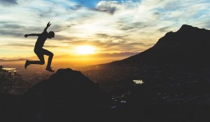 Image of man leaping in front of a sunrise